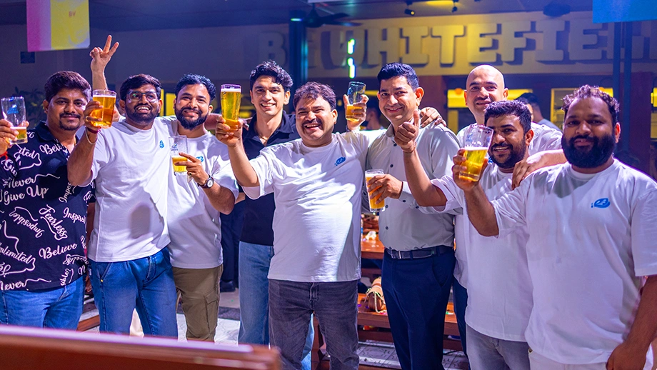 A group of smiling friends and beer enthusiasts posing together with fresh craft beer glasses at Biergarten in Bangalore.