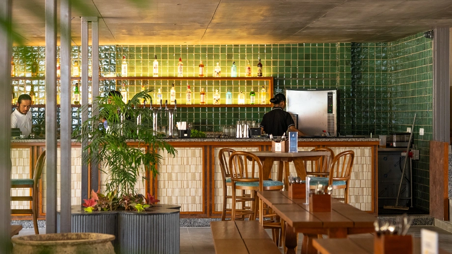 Biergarten's modern bar counter with green tiled backdrop and wooden seating, a top choice among brunch places in Whitefield.